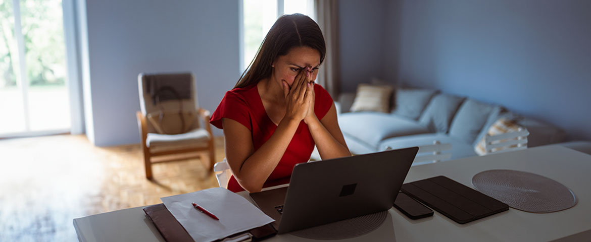 Une femme assise à sa table à manger consultant son ordinateur