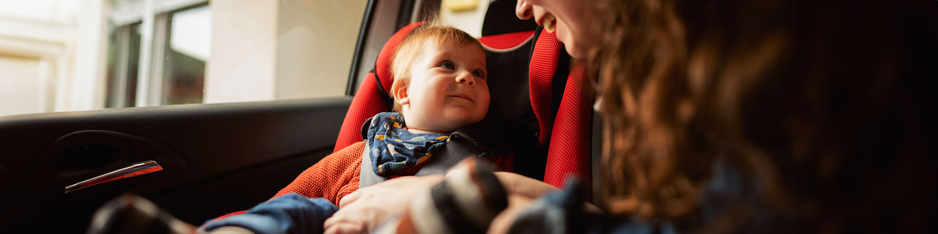 Une femme qui installe son bébé dans un siège auto