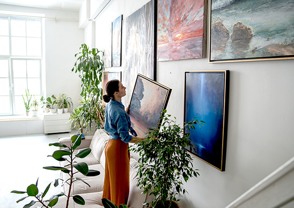 une femme qui accroche des tableaux