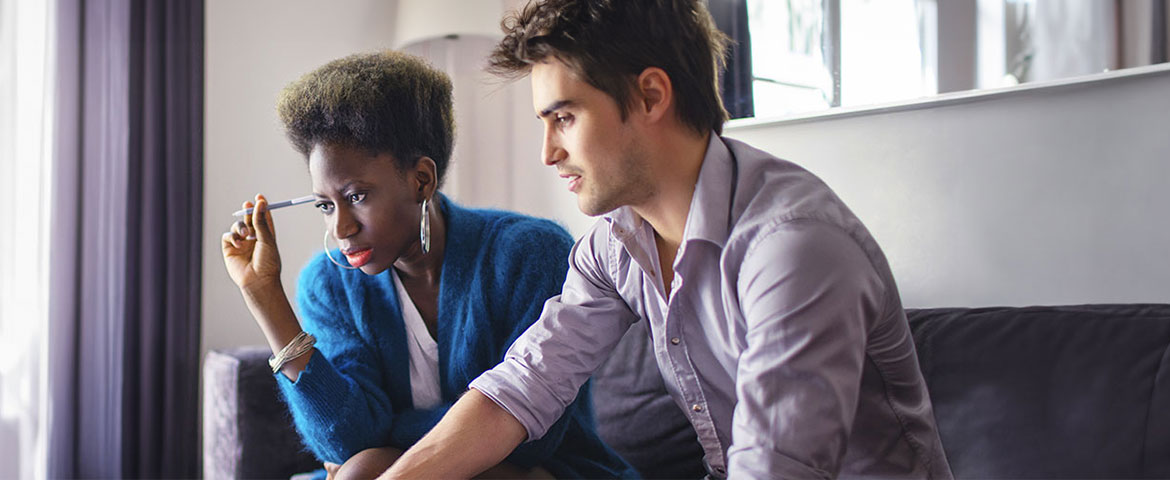 couple assis sur un canapé face à un ordinateur