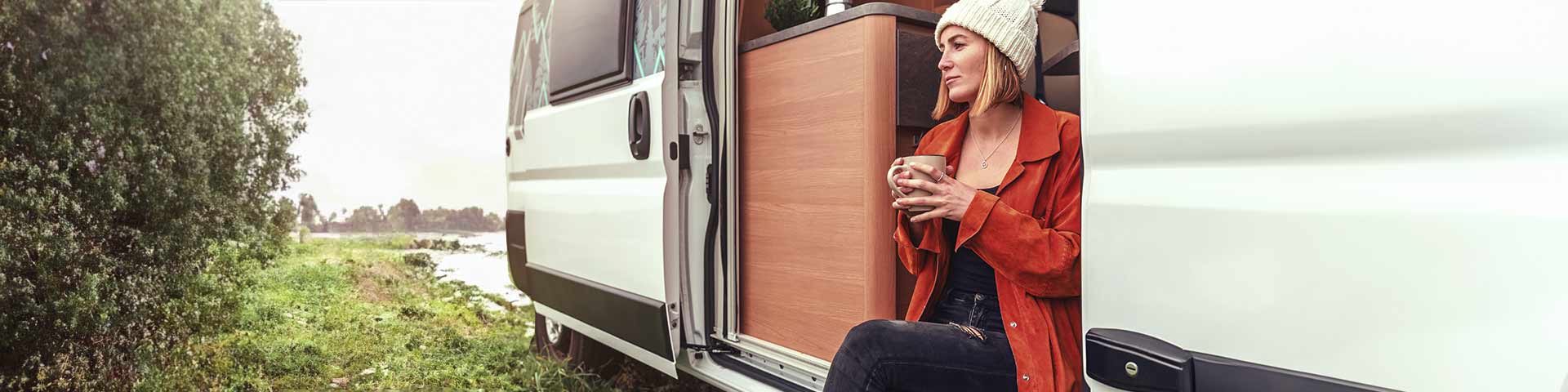 Une femme assise qui boit du thé dans son camping car