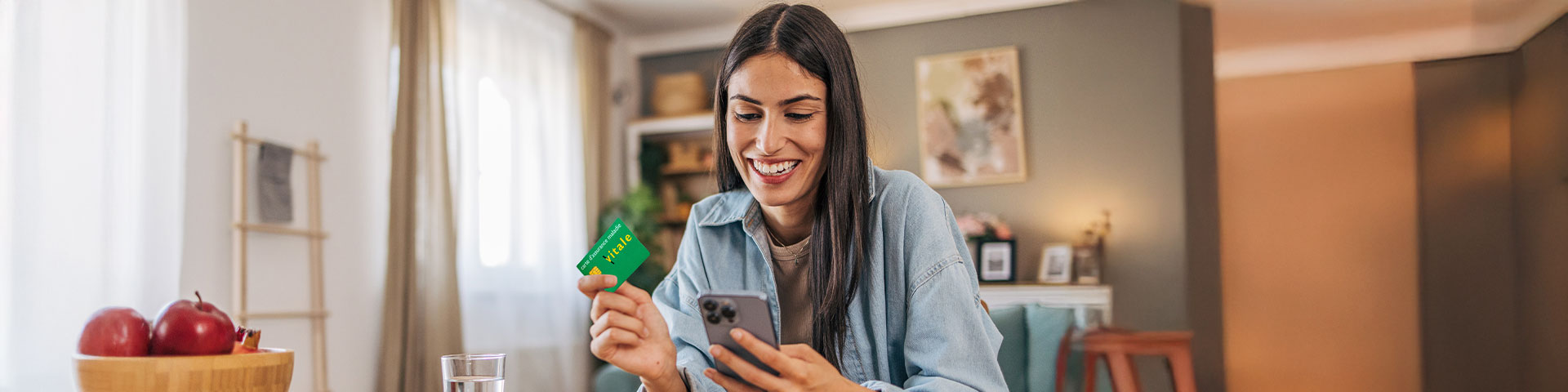 femme tenant dans ses mains son smartphone et sa carte vitale