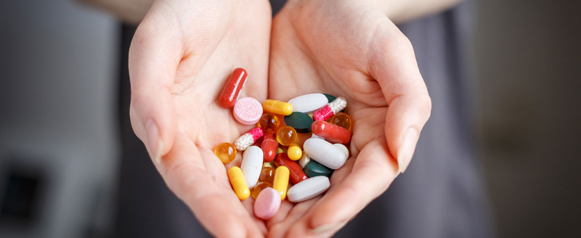 gros plan sur des mains tenant des pilules de toutes les couleurs
