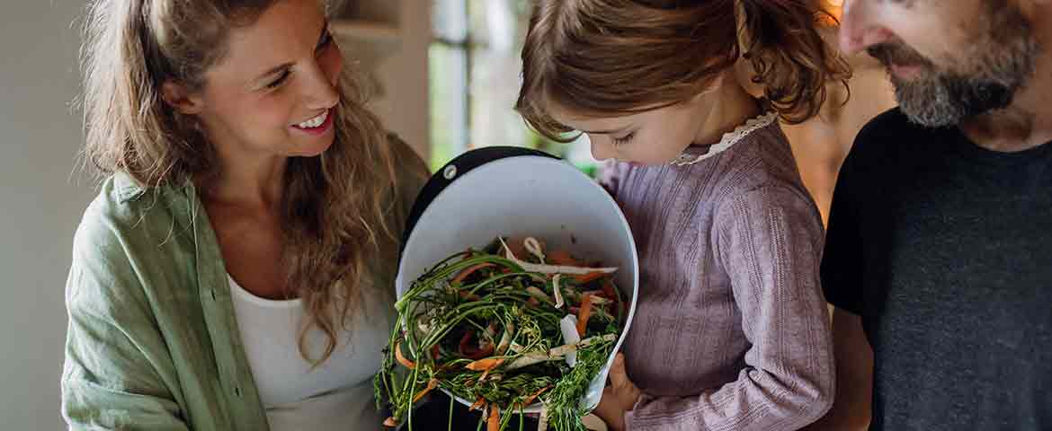 Une famille, parents et leur fille, trie leurs déchets alimentaire