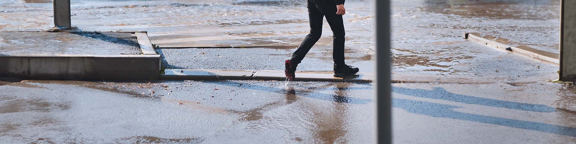 Un passant traverse une rue en crue