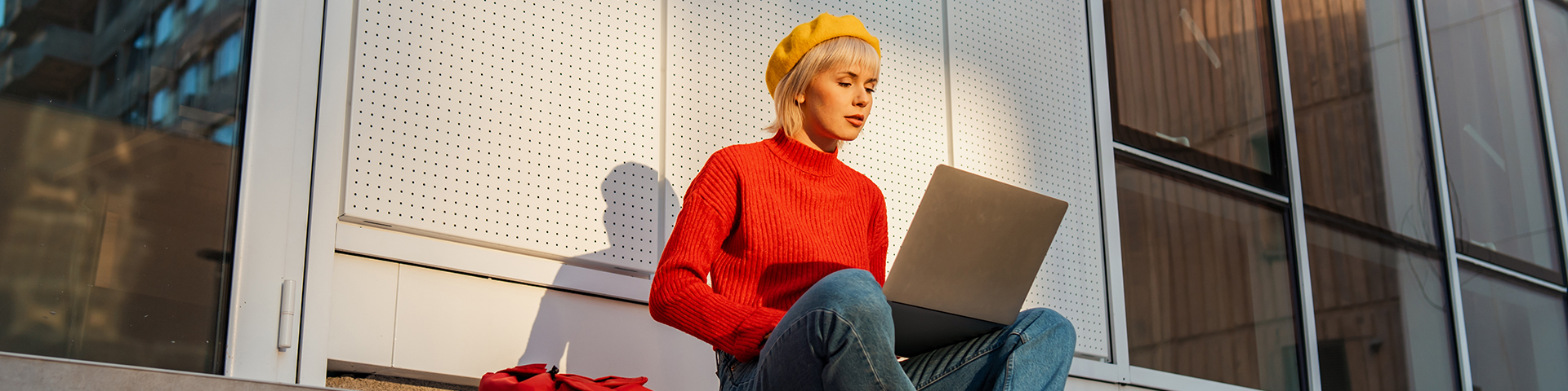 femme sur son laptop assise en extérieur sur des marches