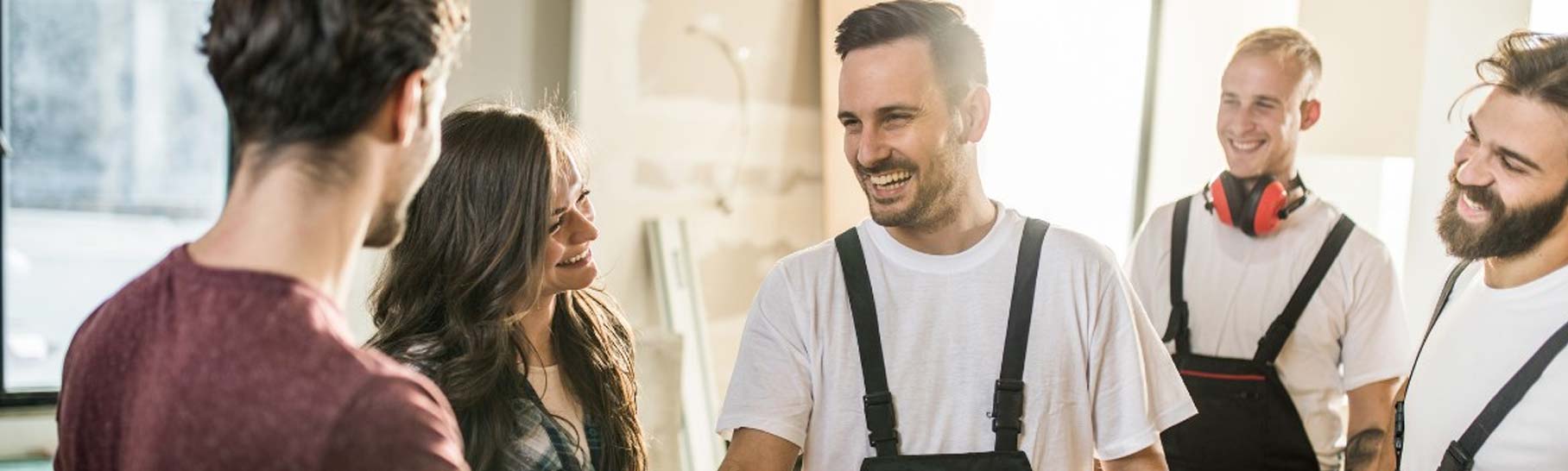 Groupe d'artisans discutant d'un projet de rénovation énergétique avec une cheffe d'entreprise