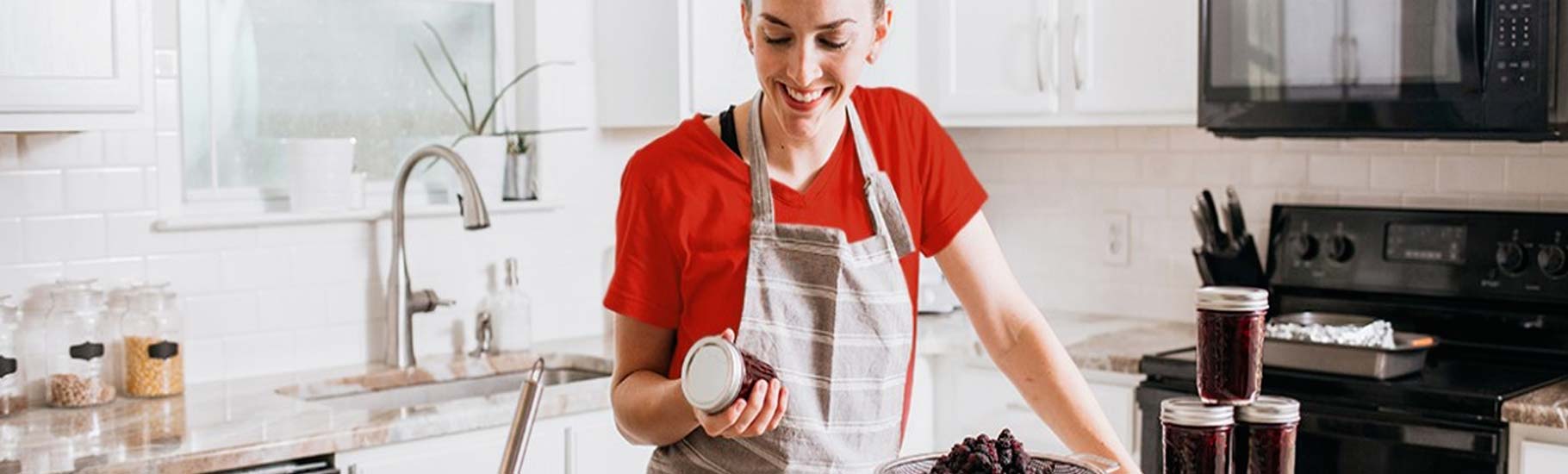 Jeune femme remplissant des bocaux de confiture après stérilisation