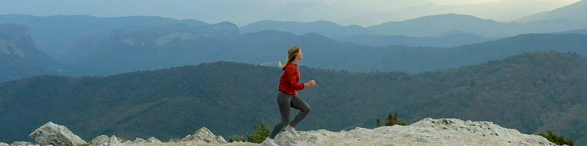Jeune femme courant au sommet d'une montagne