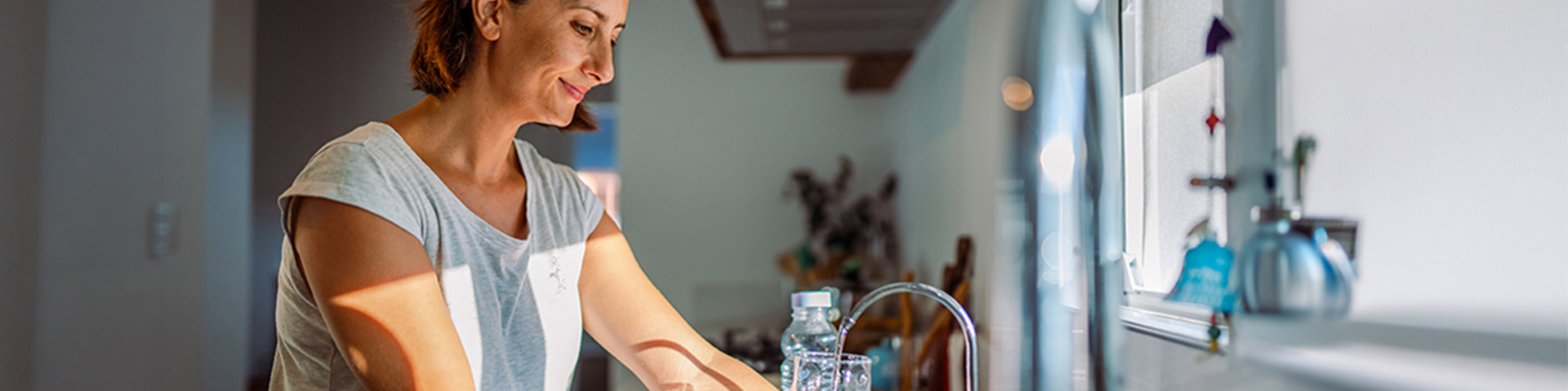 femme faisant couler l'eau du robinet de sa cuisine