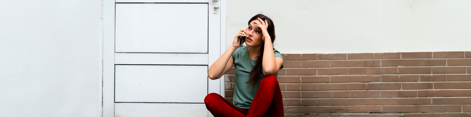 Femme au téléphone devant sa porte d'entrée