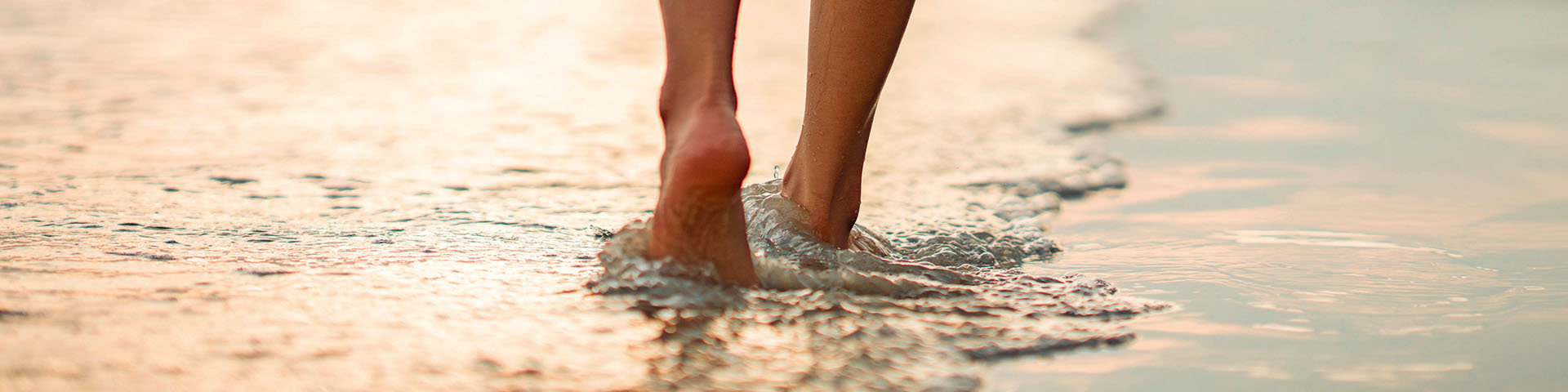 pieds nus marchant au bord de l'eau sur le sable
