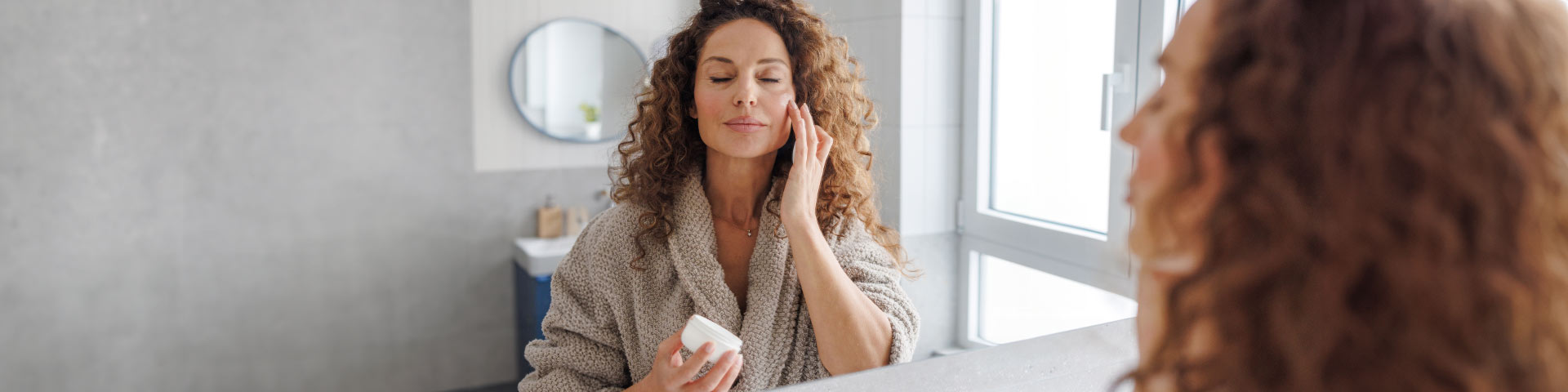 une femme qui se met de la crème sur le visage