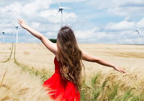 Jeune femme dans un champ de céréales avec des éoliennes au fond