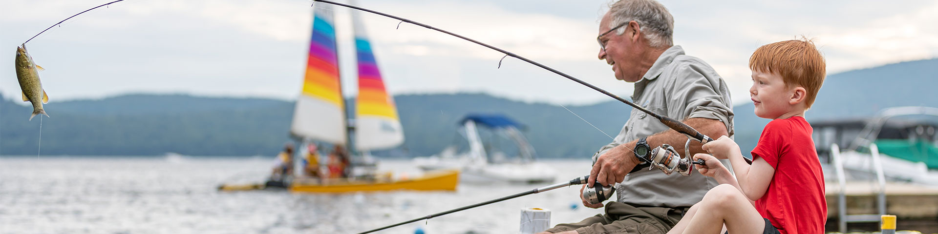 Grand-père et son petit-fils pêchant devant l'entrée d'un port