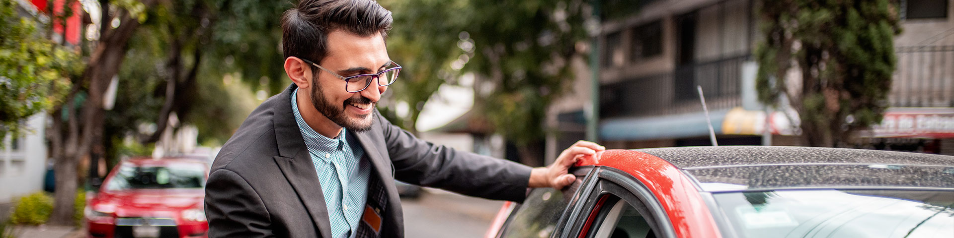 Jeune homme devant une voiture rouge