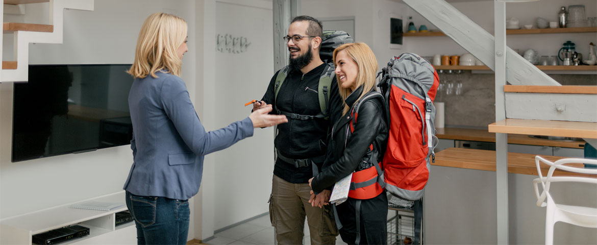 femme accompagnant un couple de voyageurs avec des clefs.