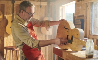 un artisan dans son atelier qui fabrique une guitare