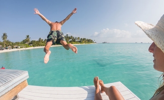 Couple au bord d'un lagon, l'homme se jette à l'eau
