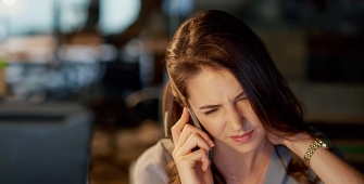 Une femme au téléphone gênée par une douleur au cou