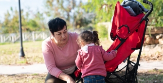 Une nounou qui parle avec l'enfant qu'elle garde dans un parc