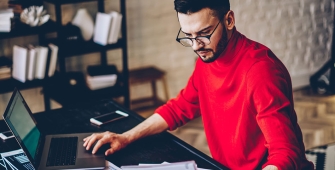 Un homme avec un pull rouge à son bureau 