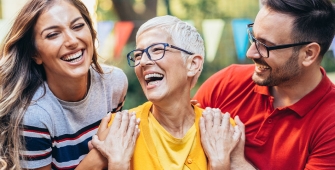 Une femme âgée qui rigole avec deux autres personnes 