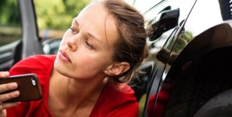 Une femme qui prend en photo sa voiture accidentée 
