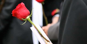 une rose et un livret tenue en main par une personne habillée en noir