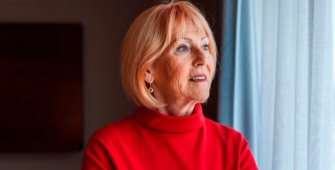 femme au pull rouge regardant par la fenêtre