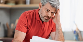 homme d'âge mûr se tenant la tête face à des documents