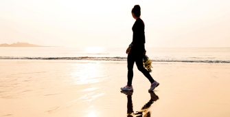 Silhouette d'une femme marchant sur le sable en bord de mer