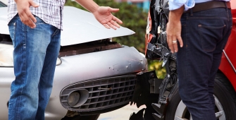 Deux personnes qui montrent les dégâts sur leur voiture après un accident