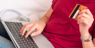 Quelqu'un sur un ordinateur avec une carte bancaire à la main