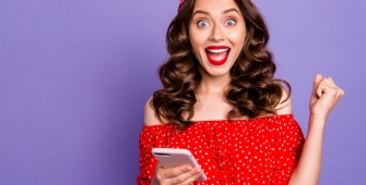 Une femme contente qui tient son téléphone 