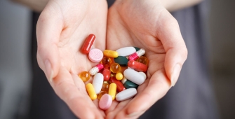 gros plan sur des mains tenant des pilules de toutes les couleurs