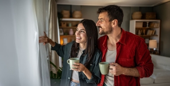 Un couple qui regarde par la fenêtre du salon