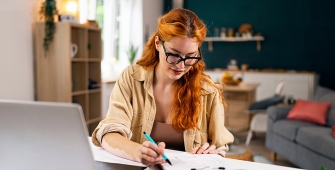 Jeune femme 30-40 ans rousse travaille chez elle