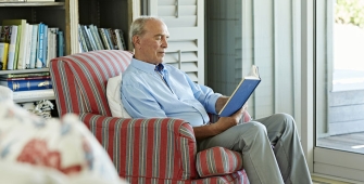 senior dans son intérieur lisant un livre