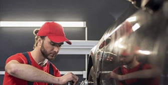 Un garagiste avec une casquette rouge répare une voiture