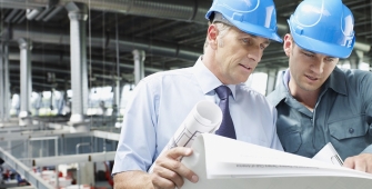 2 techniciens ingénieurs en entreprise regardent des plans