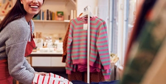 Une commerçante expose des vêtements dans sa boutique