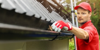 Un homme qui nettoie une gouttière 