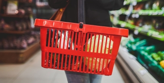 Personne tenant un panier de courses rouge dans un supermarché