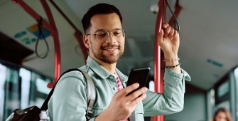 Jeune homme debout dans un bus, regardant son téléphone portable