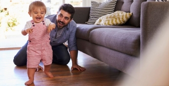 Papa jouant avec son fils sur le sol du salon (article sur le congé parental)