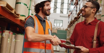 Deux hommes dans un entrepot qui se serrent la main