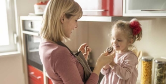 Une maman donne un biscuit à sa petite fille