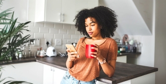 Une femme qui boit son café dans sa cuisine