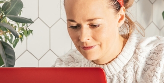 Jeune femme devant son ordinateur (article sur la déclaration aux impôts des sommes gagnées dans le cadre de l'économie collaborative)